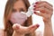 Young woman with home made pink cotton face mouth virus mask dropping anti bacterial alcohol rubbing gel on hand, detail to white