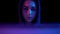 Young woman in a hood with a laptop. Hacker makes a hack through a laptop. Blue and red light falls on a woman on a