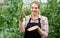 Young woman horticulturist in gloves picking harvest of pease