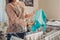 Young woman housewife hanging clean clothes on dryer after washing at home. Housekeeping and household chores