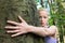 Young woman hugging a tree.