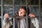 A young woman imprisoned sadly looks out from behind bars in a medieval prison. Portrait of a criminal in vintage clothes at a