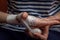 The young woman independently bandages the damaged hand with a white gauze bandage. Close-up
