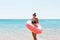 Young woman with inflatable ring cold shivering sad crossed arms black bikini swimsuit standing in sea water. Summer holidays and