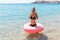 Young woman with inflatable ring cold shivering sad crossed arms black bikini swimsuit standing in sea water. Summer holidays and