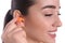 Young woman inserting foam ear plug on white background, closeup