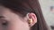 Young woman inserts a hearing aid into her ear close up