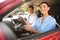 Young woman and instructor in car outdoors. Driving school