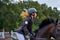 Young woman jockey in white black dress, takes part in equestrian competitions.