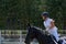 Young woman jockey in white dress and black boots, takes part in equestrian competitions