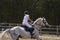 Young woman jockey in white dress and black boots  takes part in equestrian competitions.