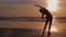 Young woman jogger on the seashore doing stretching exercises