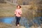 Young woman jogging in the park near the pond in the cold sunny morning