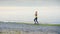 A young woman jogs along the shore of the sea or a lake, autumn, morning