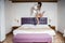 Young woman jumping on bed in hotel room