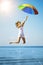 Young woman jumping with rainbow umbrella on the beach. Scene of