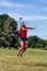 Young woman jumping and smiling with cell phone outdoors