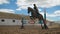Young woman jumps horse over an obstacle during her training in an arena