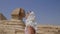 Young woman is kissing the Great Sphinx of Giza. Girl is wearing a head wear.