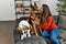 Young woman kissing and hugging dogs sitting on sofa at home