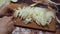 Young woman in the kitchen cutting the onions with knife on wooden cutting board