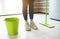 Young woman on kitchen during quarantine. Stand alone on clean floor after washing it with mop and water. Bucket on side