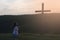 Young woman kneeling. Praying. Hands in prayer. Near the wooden cross.