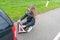 Young woman kneels behind the car and mounts the warning triangle