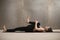 Young woman in Knees to Chest, Apanasana pose, grey studio