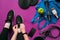 Young woman laces sneakers, preparing for training. Bottle of water, yoga mat, phone, headphones on purple background