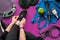 Young woman laces sneakers, preparing for training. Bottle of water, yoga mat, phone, headphones on purple background