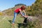 Young woman laces up the jogging shoes against the blue sky and forest after a pedestrian walk sunny day