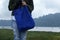 Young woman on the lake holding a blue women foldable shopping bag reusable eco . Love nature and earth concept.