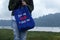 Young woman on the lake holding a blue women foldable shopping bag reusable eco with text message - Just say no to plastic bags.