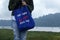 Young woman on the lake holding a blue women foldable shopping bag with text message - Save earth. No more plastic bags.