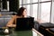 Young woman with a laptop in a coffee shop thoughtfully looks out the window