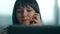 Young woman laughing on the phone sitting at her desk in an office behind her computer