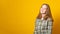 Young woman laughs, shows a beautiful smile, dressed in a plaid shirt, on a yellow background. Banner copy space