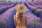 Young woman in lavender field on sunset. Back view of girl in blooming lavender meadow