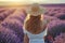 Young woman in lavender field on sunset. Back view of girl in blooming lavender meadow