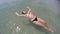 Young woman laying relaxing on the waves in beautiful azure carribean sea holidays fun vacation concept