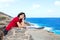 Young woman leaning against stone wall overlooking Hawaiian ocean