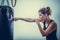 A young woman leans hands of black punching bag