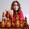 Young woman learning chess while sitting in a mask at a chessboard, lessons during the coronavirus epidemic