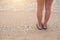 Young woman legs in flipflop sandals on sea beach.