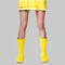 Young woman legs in Illuminating yellow dress and rubber boots on Ultimate Gray background