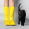 Young woman legs in Illuminating yellow rubber boots on tiptoe with black cat on Ultimate Gray background