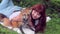 Young woman lies on grass in park with red fox outdoors.