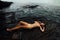 young woman lies on a rock ocean shore. Beautiful girl on stony background