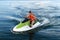 Young woman in a life jacket rides a water bike on a lake in summer